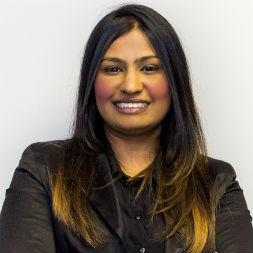 Person smiling with crossed arms, wearing a dark shirt.