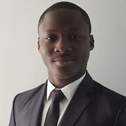 Portrait of a person wearing a dark suit and tie, smiling slightly.