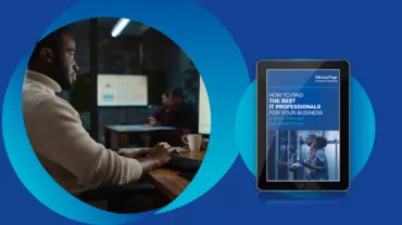 Person working at a computer with a tablet displaying a business guide.