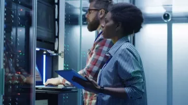 People working in a server room, examining equipment.