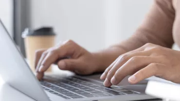 Person typing on a laptop at a desk.