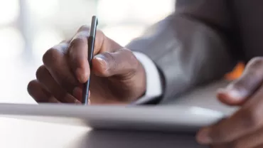 Person writing on a digital tablet with a stylus.