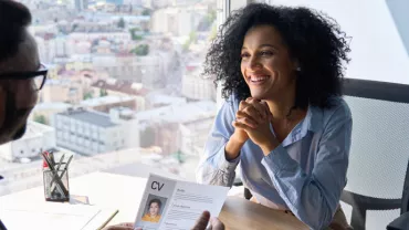 Person smiling during an interview in an office with a city view.
