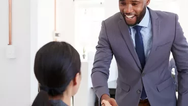 Two people shaking hands in a modern office setting.