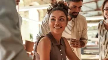 Group of people smiling and talking in a bright office.