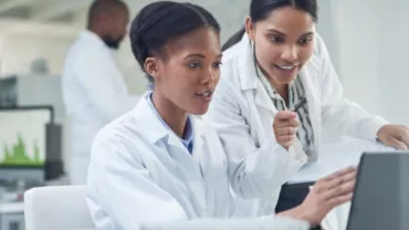 Scientists working together on a laptop in a lab.
