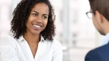 Two people in a professional meeting, one smiling.