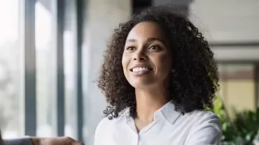 A person smiling and greeting someone in a well-lit office.