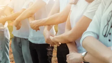 A line of people standing outside, holding each other's arms.