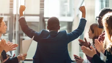 Person celebrating in front of a clapping group.