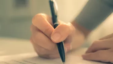 Person writing with a pen on paper.