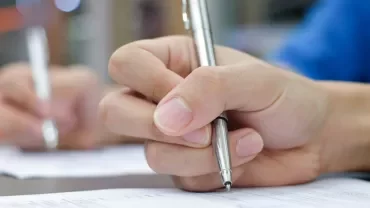 Person writing on paper with a pen.