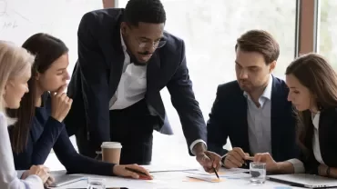 Team collaborating at a conference table with documents and a laptop.
