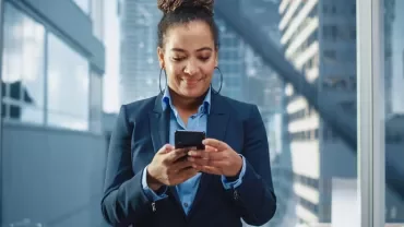 Person using smartphone in modern office elevator.