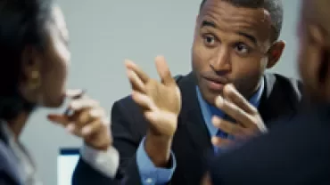 Personne gesticulant lors d'une réunion professionnelle.