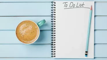 Notebook with 'To Do List' and pencil beside a cup of coffee on a blue table.