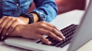 Person typing on a laptop wearing a smartwatch.