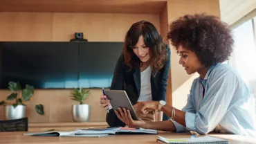 Two people collaborating on a tablet in a modern office.
