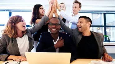 Group of people in an office celebrating with high fives.