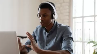Person with headphones having a video call on a laptop.