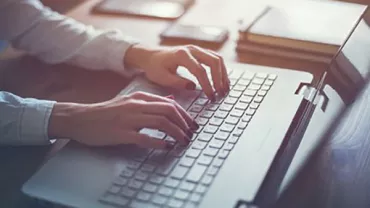 Person typing on a laptop at a desk.