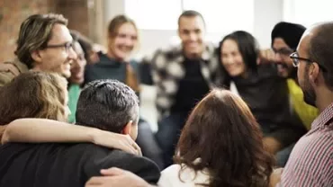 A group of people sitting close together, smiling and hugging.