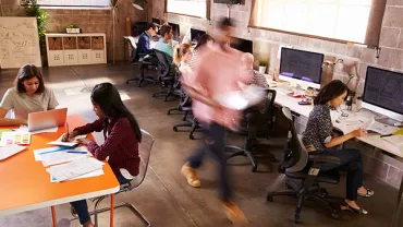 Bureau en espace ouvert avec des personnes travaillant à des bureaux et ordinateurs.