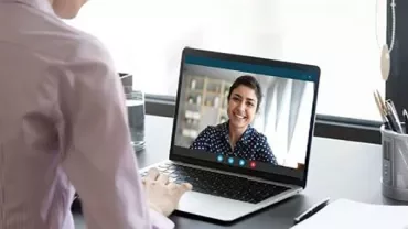 Person on a video call with another person on a laptop.