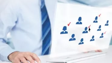Person using a computer with icons of people and checkmarks on the screen.