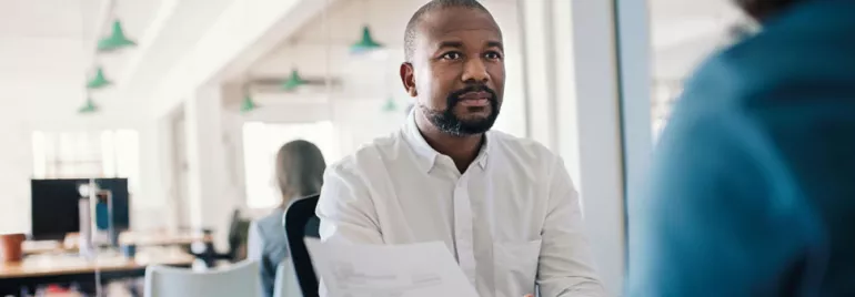 Personne tenant un document lors d'une réunion dans un bureau.