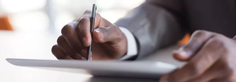 Une personne écrit sur une tablette numérique avec un stylet.