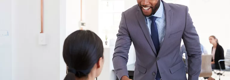 Two people shaking hands in a modern office setting.
