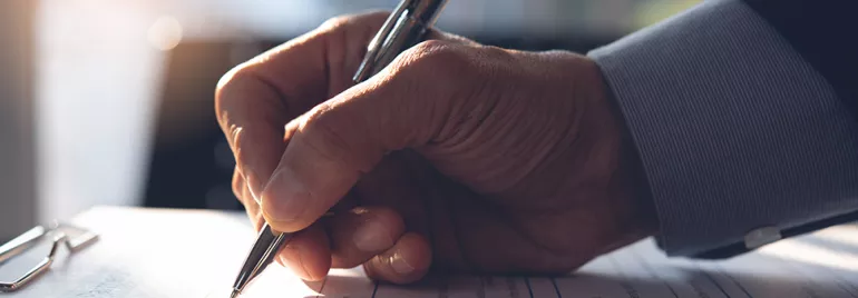 A person signs a document using a pen.