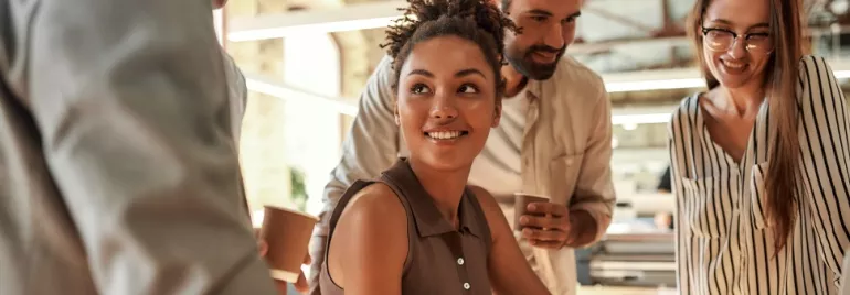 Group of people smiling and talking in a bright office.