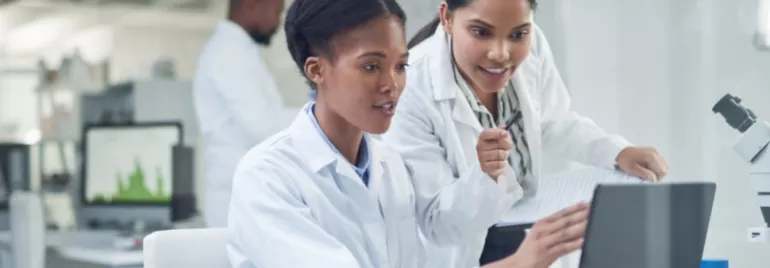 Scientists working together on a laptop in a lab.