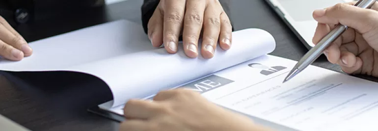 Two people reviewing a resume at a desk.
