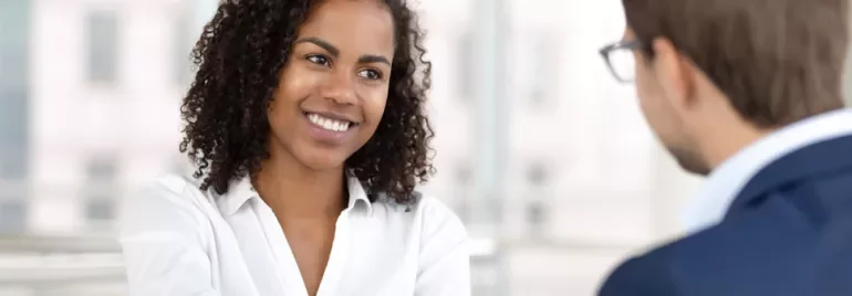 Two people in a professional meeting, one smiling.