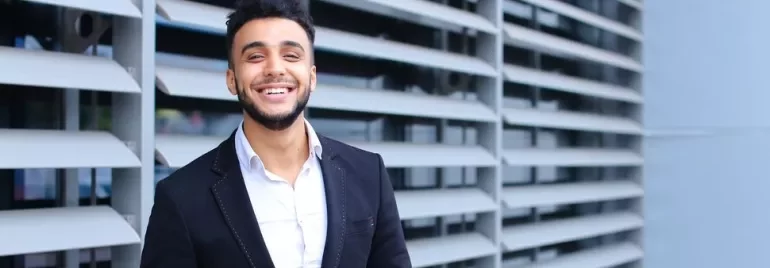 Person smiling in front of modern architectural background.