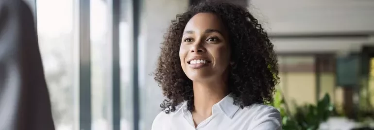 A person smiling and greeting someone in a well-lit office.