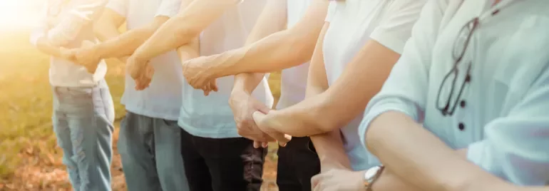A line of people standing outside, holding each other's arms.