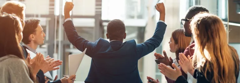Person celebrating in front of a clapping group.