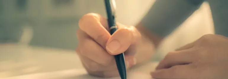 Person writing with a pen on paper.