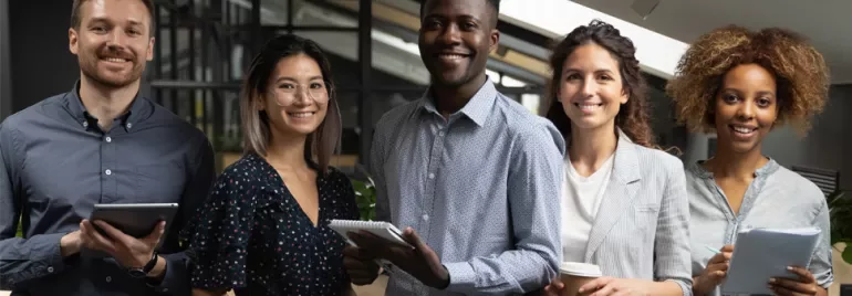 Team of five people smiling in an office setting.