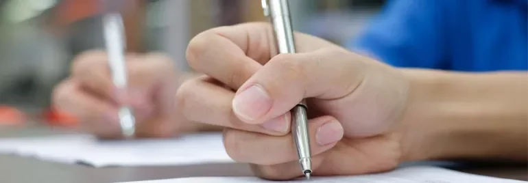 Person writing on paper with a pen.