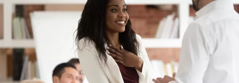 Person smiling and listening during a meeting in an office setting.