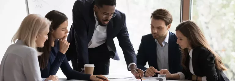 Team collaborating at a conference table with documents and a laptop.