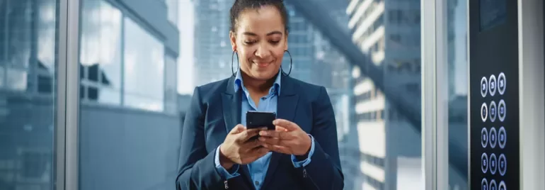 Personne utilisant un smartphone dans un ascenseur moderne.