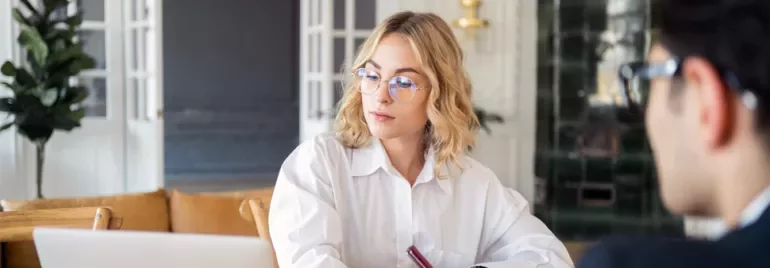 Person wearing glasses working on a laptop in a cozy office.