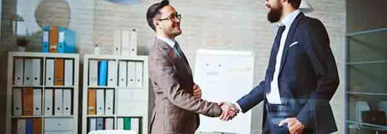 Two people shaking hands in a modern office setting.