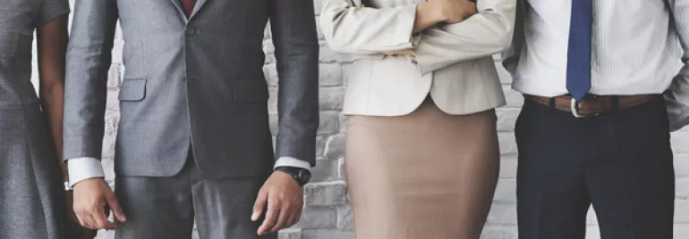 People in business attire standing against a brick wall